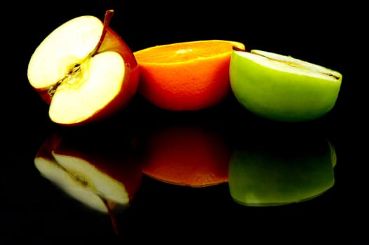 Apple and oranges isolated against a black background
