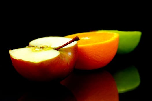 Apple and oranges isolated against a black background