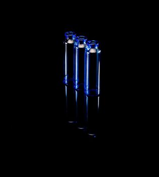 blue glass vials over black background backlit