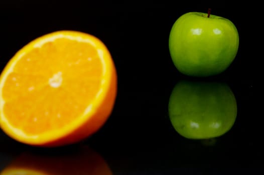 Apple and orange halves isolated against a black background