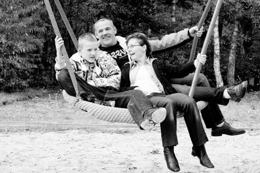 Happy young family in the swing on the playground