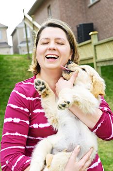 Portrait of laughing woman holding golden retriever puppy