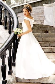 Beautiful bride in white dress stood on steps.