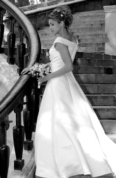 Beautiful Bride in traditional white wedding dress stood on steps.