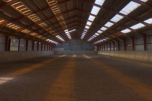 Interior of Riding Hall with sunlight beaming through roof windows.