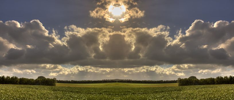 Powerful sun through clouds on peaceful rural landscape.