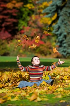 boy jumping in pile of leaves