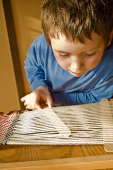 boy in blue preparing loom for weaving