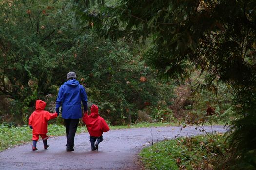 mother and two children walking down road in rain coats