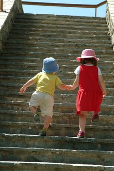 girl helping small boy up stairs