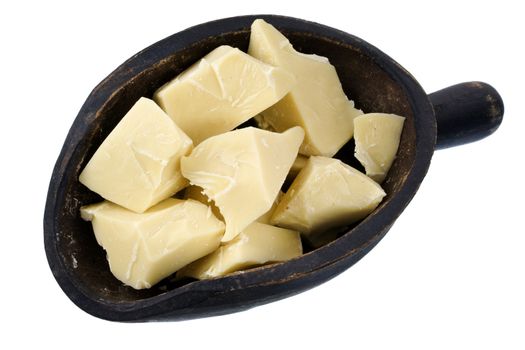 Rough chunks of white chocolate on a primitive, wooden scoop, isolated 