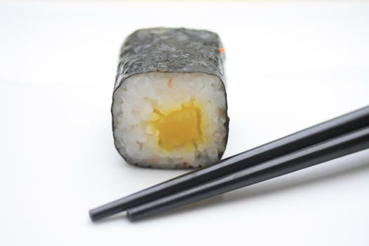 A piece of makisushi, rice rolled in seaweed and chopsticks