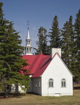 a small chapel with a red roof surrounded by trees