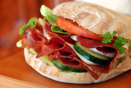 big appetizing sandwich with red ham meat, cucumber and tomatoes