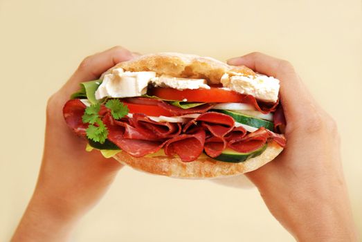 appetizing big fresh sandwich with ham, cheese and vegetables in hands