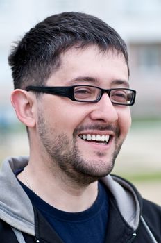 Portrait of a young male caucasian student with beard and glasses smiling