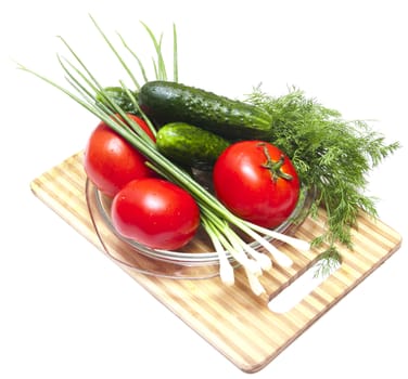 Cucumber, tomatoes and greens, close up on wooden board