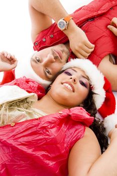 cheerful young couple wearing christmas hat lying down on floor on an isolated white background