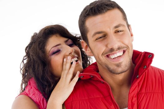 cheerful young couple whispering to each other against white background