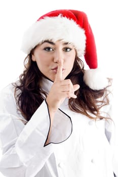 pretty chef wearing christmas hat and shushing with finger on an isolated background