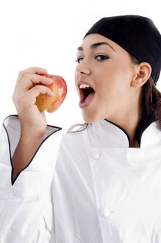 young beautiful chef eating apple on an isolated background