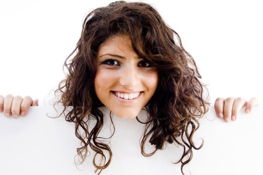 young businesswoman peeping over white board against white background