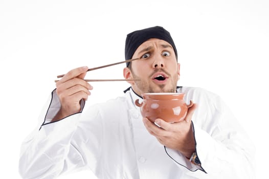 surprised young chef posing with bowl and chopstick against white background