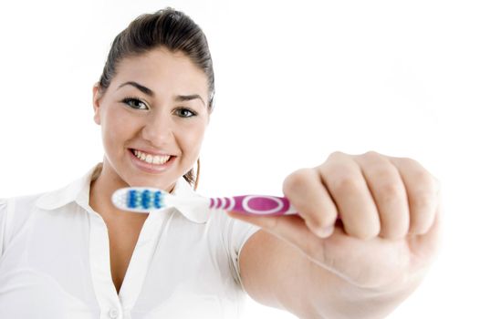 smiling female showing toothbrush against white background