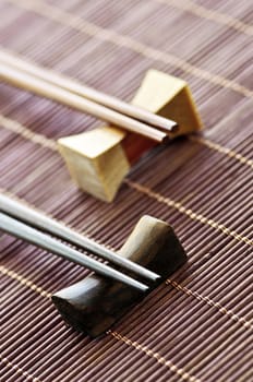 Two sets of wooden chopsticks on rests close up