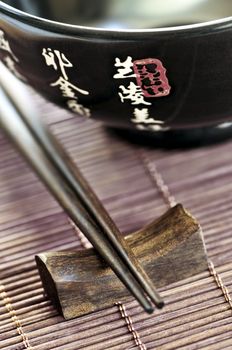 Asian rice bowl and wooden chopsticks on a rest close up