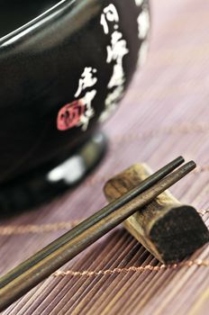 Asian rice bowl and wooden chopsticks on a rest close up