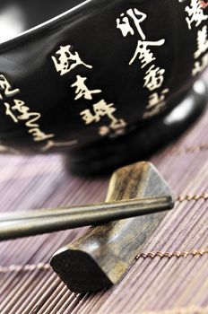 Asian rice bowl and wooden chopsticks on a rest close up