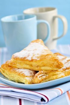 Apple turnovers pastries with coffee cups in the background