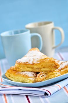 Apple turnovers pastries with coffee cups in the background