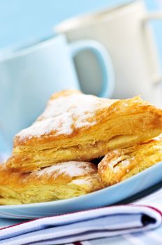 Apple turnovers pastries with coffee cups in the background