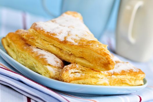 Apple turnovers pastries with coffee cups in the background