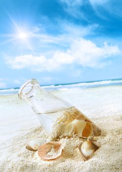 Bottle with seashells in the sand at the beach
