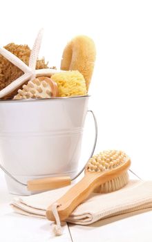 White bucket filled with sponges, scrub brushes and starfish on white