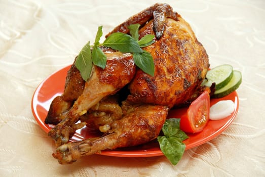 whole grilled chicken served on red plate decorated with vegetables and mint