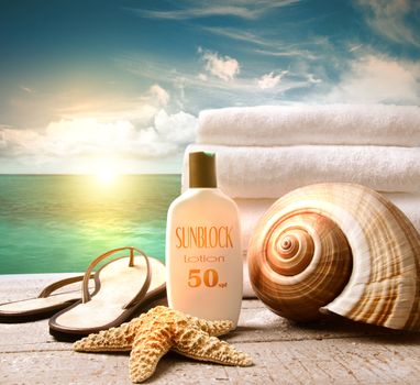 Sunblock lotion and white towels with ocean scene