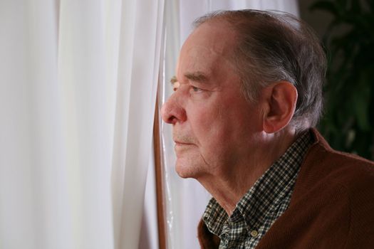 Elderly man looking out window