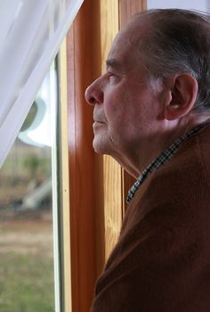 Elderly man looking out window