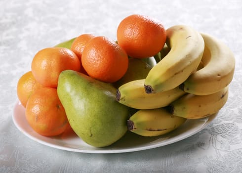 Plate of fresh fruit, clementine oranges, pears and bananas