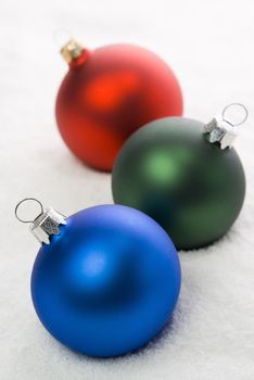 Red, Green and Blue christmas balls on the snow. aRGB.