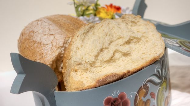 Two bread halves resting in traditional rose-painted basket.