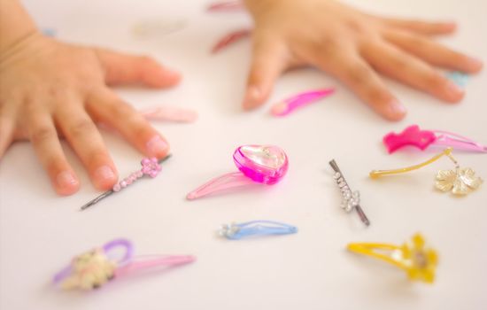 Close up of child's hands and jewelery on white.