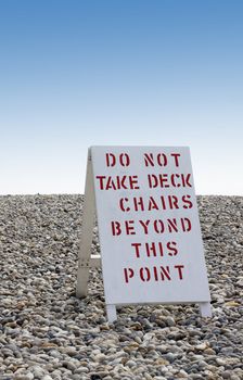 A hand painted wooden boarded beach sign set on a pebbled beach. Located in Beer, Dorset, England.