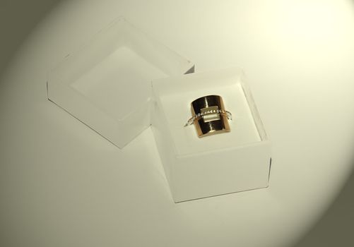 golden ring gift in paper box over white background