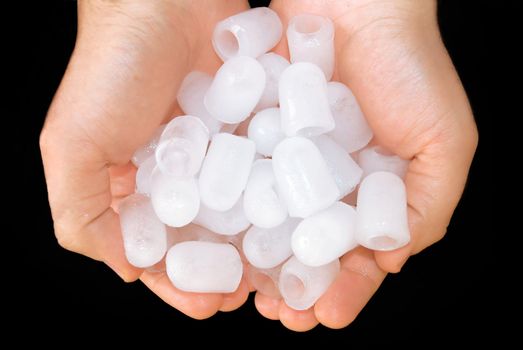 pieces of ice in hand close up over black background