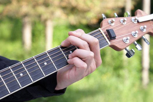 A closeup shot of a young man playing his guitar.
